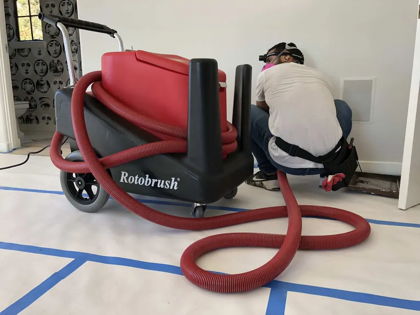 Technician cleaning a floor vent with the work area taped and protected